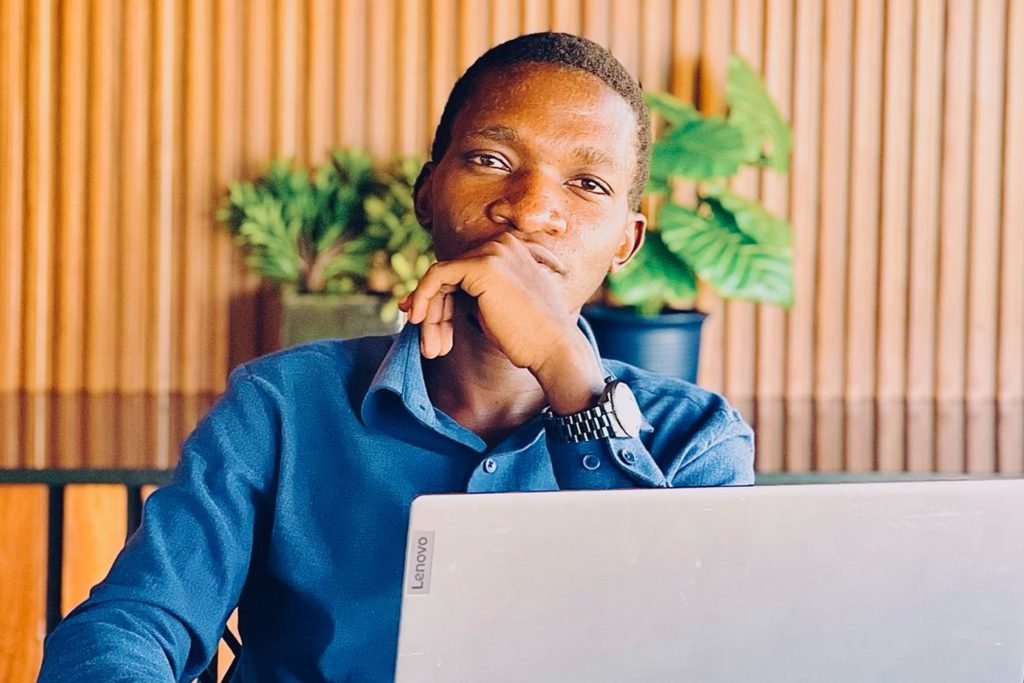 Mukiibi Hamza Katende at his laptop, resting his chin on his hand